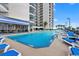 Exterior view of pool with lounge chairs next to tall building and sunny sky at 200 76Th Ave. N # 301, Myrtle Beach, SC 29572