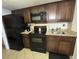 Functional kitchen featuring black appliances, granite countertops, and dark wood cabinets at 200 76Th Ave. N # 608, Myrtle Beach, SC 29572