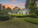Charming single-story home surrounded by lush greenery and trees beneath a vibrant, colorful sunset at 28 Torrens Pl., Pawleys Island, SC 29585