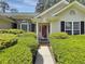Close-up of the charming entryway adorned with brick accents and vibrant green landscaping, creating a welcoming path at 28 Torrens Pl., Pawleys Island, SC 29585