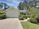Inviting one-story home with a well-manicured lawn, attached garage, and cozy facade, showcasing a welcoming curb appeal at 28 Torrens Pl., Pawleys Island, SC 29585