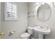 Bright half bathroom featuring a pedestal sink, oval mirror, and plantation shutters at 306 River Rock Ln. # 1306, Murrells Inlet, SC 29576