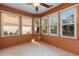 This sunroom features an orange paneled wall with neutral tile floor, many windows, and a ceiling fan at 3107 Robyn Ct., Little River, SC 29566