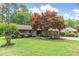 Charming brick home featuring a well-manicured lawn and beautiful landscaping, including a vibrant Japanese maple at 33 Brassie Dr., Carolina Shores, NC 28467