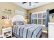 Bright bedroom showcases striped bedding, window with blinds, and decorative shelves, creating an inviting atmosphere at 3757 Kingsley Dr., Myrtle Beach, SC 29588