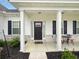 Inviting front porch with columns, a black front door, and a cozy seating area at 40 Little Peru Ct., Georgetown, SC 29440