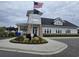 Community clubhouse with American and South Carolina flags, manicured landscaping, and ample parking at 448 Papyrus Circle # 448, Little River, SC 29566