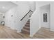 Bright hallway featuring wood floors, a staircase, and white walls with decorative artwork at 452 Sun Colony Blvd., Longs, SC 29568