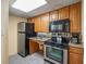 A well-organized kitchen featuring wooden cabinets, a stainless steel refrigerator, and sleek black appliances at 6804 N Ocean Blvd. # 1049, Myrtle Beach, SC 29572