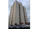 Exterior view of a condominium building with a parking lot and cloudy skies at 7509 N Ocean Blvd. # 1205, Myrtle Beach, SC 29572