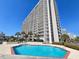 Exterior view of the outdoor pool area with palm trees and high-rise condos in the background at 9820 Queensway Blvd. # 1603, Myrtle Beach, SC 29572