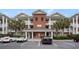 Attractive condo building featuring palm trees, a brick facade, and covered balconies with white railings at 1000 Ray Costin Way # 107, Garden City Beach, SC 29576