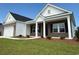 Inviting brick and vinyl sided home featuring a charming front porch with white columns and well-manicured lawn at 1033 Jase Dr., Longs, SC 29568