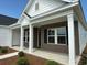 Charming brick home with covered porch, supported by white columns, and neat landscaping at 1033 Jase Dr., Longs, SC 29568