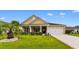 Charming tan home featuring a well-manicured lawn, complemented by a two-car garage and inviting front porch at 1035 Brentford Pl., Myrtle Beach, SC 29579