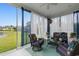Cozy screened-in porch with comfortable seating, decorative curtains, and views of the lush backyard and pond at 1035 Brentford Pl., Myrtle Beach, SC 29579