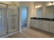 Well-lit bathroom showcasing a glass shower, double vanity with dark countertops and wood-look flooring at 1037 Jase Dr., Longs, SC 29568