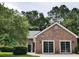 Exterior featuring brick facade, black front door, driveway, lush trees, and landscaping at 104 Jessica Lakes Dr., Conway, SC 29526