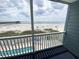 Balcony view with a swimming pool overlooking a sandy beach and pier at 116 S Waccamaw Dr. # 205, Murrells Inlet, SC 29576