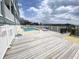Exterior shot of a pool surrounded by a wooden deck and fenced in area overlooking a beach view at 116 S Waccamaw Dr. # 205, Murrells Inlet, SC 29576