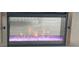 Modern fireplace with a glass front showcasing purple decorative stones and vibrant flames at 1311 S Ocean Blvd. # B-1, North Myrtle Beach, SC 29582