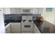 Corner view of kitchen with granite countertops, white cabinets and appliances at 1311 S Ocean Blvd. # B-1, North Myrtle Beach, SC 29582