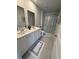 Bathroom featuring a double sink vanity, framed mirrors, and a glass-enclosed shower, offering a clean aesthetic at 1565 Jardine Loop, Little River, SC 29566