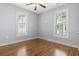 Bright bedroom features wood floors, gray walls, ceiling fan, and sun-filled windows with plantation shutters at 18 Coastal Breeze Trail, Pawleys Island, SC 29585