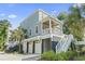 Charming elevated coastal home featuring a covered porch, white railings, and convenient ground-level garage at 18 Coastal Breeze Trail, Pawleys Island, SC 29585