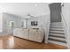 Spacious living room with hardwood floors, a sectional couch, windows with shutters, and staircase access at 18 Coastal Breeze Trail, Pawleys Island, SC 29585