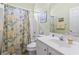 Clean bathroom featuring a white vanity, toilet, and shower with a floral curtain at 205 Carriage Lake Dr., Little River, SC 29566