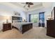 Main bedroom with a ceiling fan, tray ceiling, carpet, and a dresser at 205 Carriage Lake Dr., Little River, SC 29566