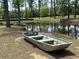 Charming view of a pond with a small boat, framed by tall trees, creating a serene and rustic landscape at 4074 Center Rd., Georgetown, SC 29440