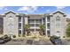 Three-story condo building featuring stone accents, white railings, balconies, and palm trees in a paved parking area at 4737 Wild Iris Dr. # 203, Myrtle Beach, SC 29577