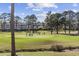 Scenic golf course view with players, putting green, sand trap, trees, and building in background at 4737 Wild Iris Dr. # 203, Myrtle Beach, SC 29577