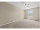 Bright, empty bedroom with beige walls, a ceiling fan, neutral carpet, and a window overlooking the yard at 480 Dandelion Ln., Myrtle Beach, SC 29579