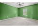 Bright, empty bedroom with green walls, a ceiling fan, neutral carpet, and a window overlooking the yard at 480 Dandelion Ln., Myrtle Beach, SC 29579