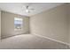 Bright, empty bedroom with beige walls, a ceiling fan, neutral carpet, and a window overlooking the yard at 480 Dandelion Ln., Myrtle Beach, SC 29579