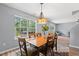 Cozy dining room with wood table, six chairs, decorative chandelier, and a large window with natural light at 480 Dandelion Ln., Myrtle Beach, SC 29579
