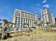 Large modern condo building featuring multiple balconies with palm trees and playground at 5300 N Ocean Blvd. # 1102, Myrtle Beach, SC 29577