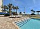Community pool featuring stairs, beach views, palm trees, and lounge chairs at 5300 N Ocean Blvd. # 1102, Myrtle Beach, SC 29577
