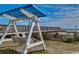 A white porch swing with a blue sunshade provides a relaxing outdoor seating area with views of the ocean at 5300 Ocean Blvd. N # 903, Myrtle Beach, SC 29577