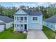 Charming two-story light blue home featuring a double garage and inviting front porches at 5545 Whitebark Dr., Myrtle Beach, SC 29577