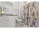 Well-lit bathroom featuring marble floors, granite countertop, modern vanity and tub with decorative shower curtain at 57 Eagle Claw Dr., Carolina Shores, NC 28467
