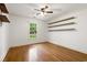 Bright bedroom featuring hardwood flooring, ceiling fan, a window with exterior views, and custom shelving at 57 River Birch Ln., Pawleys Island, SC 29585