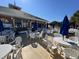 Outdoor patio with white tables and chairs with blue umbrellas providing shade at 6001 - 1864 S Kings Hwy., Myrtle Beach, SC 29575
