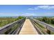 Stroll along a wooden boardwalk to the beach, surrounded by lush greenery and breathtaking views of the ocean and sky at 6803 N Ocean Blvd. # 228, Myrtle Beach, SC 29572