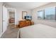 Well-lit bedroom with a TV, wooden dresser, neutral walls, and a glimpse of a living area at 9661 Shore Dr. # B-3, Myrtle Beach, SC 29572