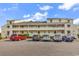 Multi-level condo building with yellow exterior and multiple cars parked in front on a sunny day at 1100 Possum Trot Rd. # D-205, North Myrtle Beach, SC 29582