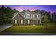 Beautiful two-story home featuring a brick facade, black shutters, lush lawn, and mature trees under a colorful dusk sky at 1303 Bermuda Grass Dr., Myrtle Beach, SC 29579